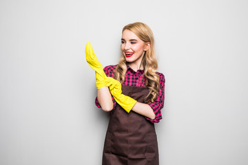 Beautiful young woman putting on protective gloves and smiling, on gray background