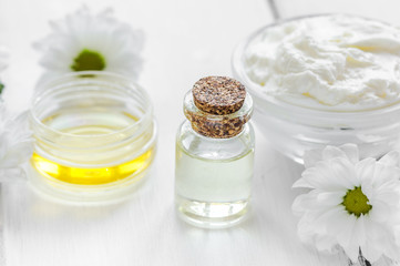 homemade cosmetics with camomile herbs on white wooden background
