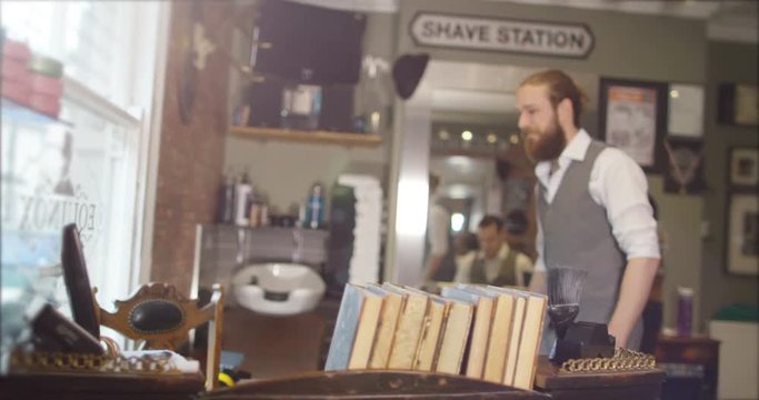  Portrait of smiling barbers behind reception desk in trendy retro barber shop. 