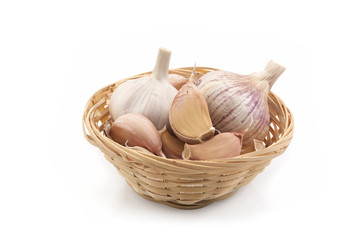 Garlic cloves in a straw basket on a white background
