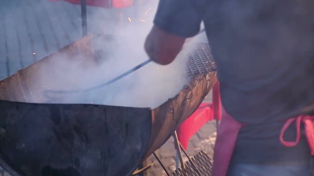 Man mixing charcoal in a smoky grill