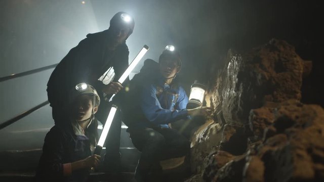  Potholers exploring cave system, shafts of light penetrating the dark