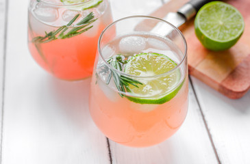sliced lime, rosemary and natural juice in glass on white table background