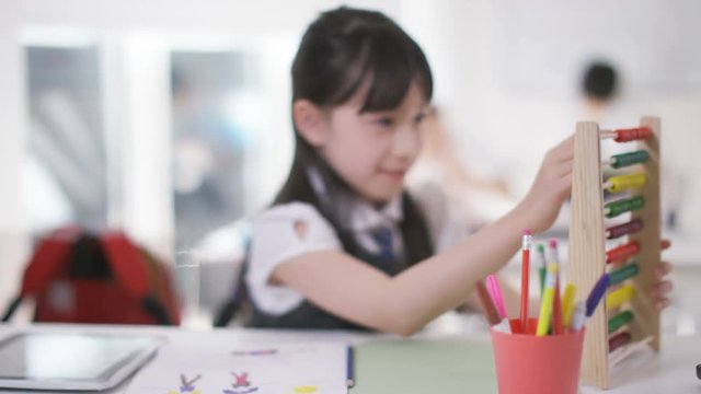  Young school children in class with little girl using abacus & computer table
