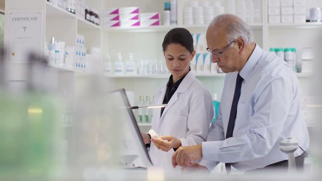 Workers in a chemist shop checking stock & discussing their work