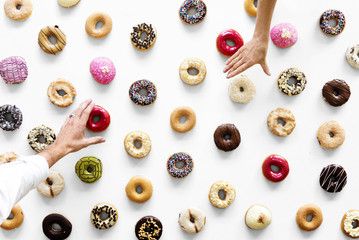 Hands selecting a variety of donut flavour