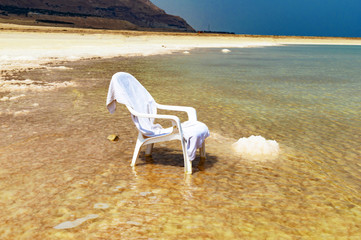 Fototapeta na wymiar White chair in the water of the Dead Sea