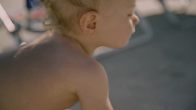 Little baby boy with a toy crawling at the beach