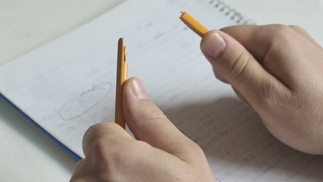 Nervous person breaking pencil to two while breakdown