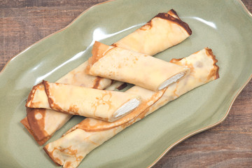 Delicious cheese blintz on green plate and wooden vintage tray