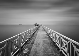 Long exposure shot of seascape and dock in black and white.