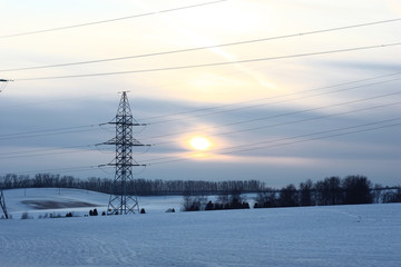 Electricity transmission of winter evening./Winter. Evening. A sunset. A field covered with snow. A high-voltage electric main.