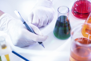 Closeup of hands of Female Laboratory Worker Dealing With Flasks Containing Liquid Chemicals.