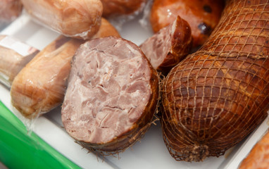 The variety of fresh smoked meat products lying on a stand at the fair