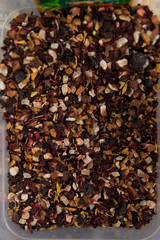 Dry tea with fruit and flower petals as background top view