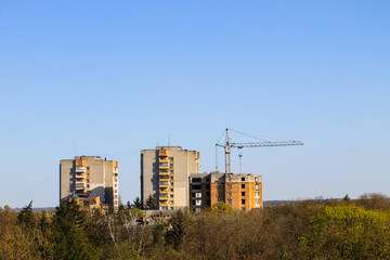 Obraz premium Building crane and building under construction against blue sky