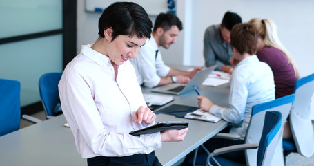 Portrait of  smiling casual businesswoman using tablet  with coworkers standing in background