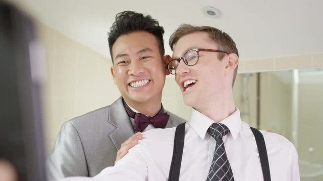  Young gay couple on wedding day pose to take a selfie with mobile phone