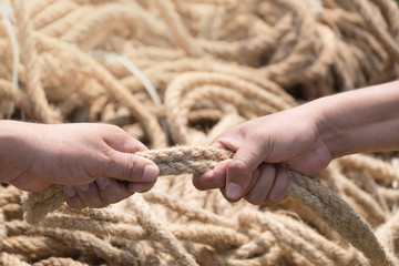 Two people are pulling a rope competing hands.