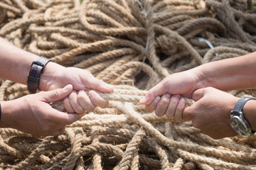 Two people are pulling a rope competing hands.
