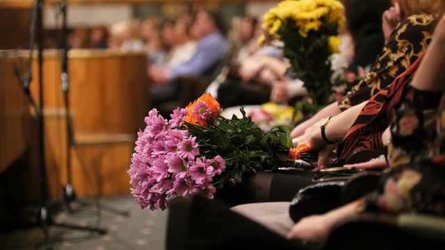 Theater hal - spectators with flowers applauding the performance on stage