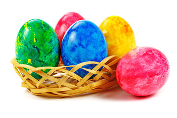 Painted Easter eggs in wicker basket on white background