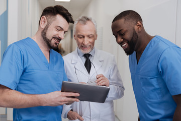 Amused aged practitioner enjoying free time with colleagues at work