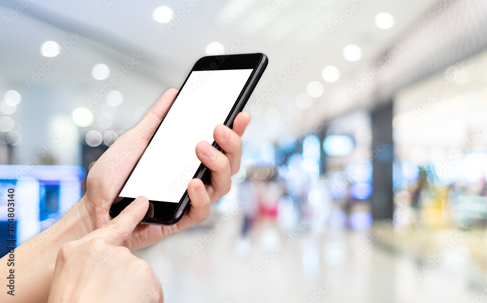 Fototapete Hand click mobile phone with blur department store background bokeh light,White screen mock up template for adding your design or your text