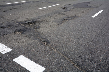 Poor quality of road repair work. Damaged asphalt road, bad road. 