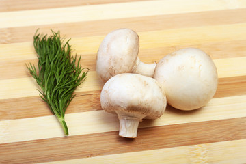 Fresh white mushrooms champignon on wooden background.