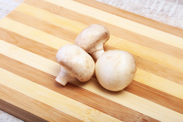 Fresh white mushrooms champignon on wooden background.