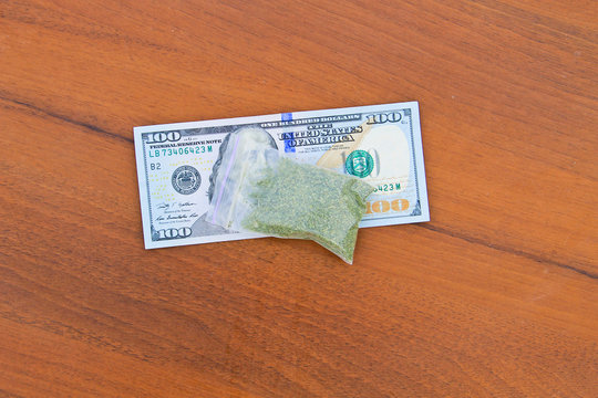 Marijuana In Packet And 100 Dollar Bill On Wooden Table