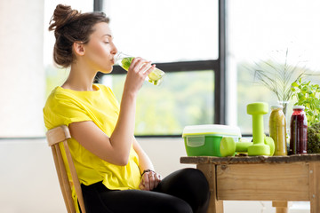 Young sports woman in yellow t-shirt drinking water with mint and cucumber. Detox concept © rh2010