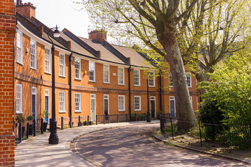 Classic British crescent with restored Victorian red brick houses on a local road with small garden in front - 144806506
