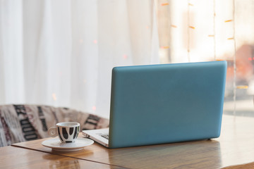 A blue laptop is on the table in the coffee house