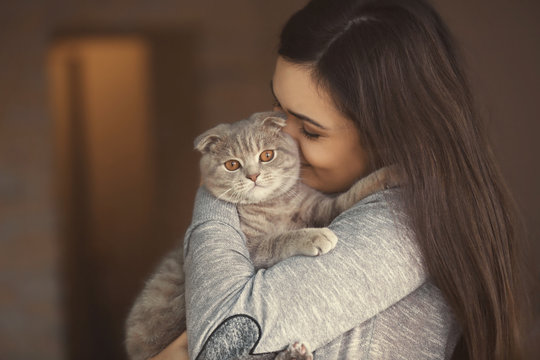Beautiful young woman with cute cat resting at home