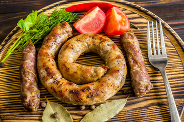 Fried sausage on a beautiful wooden tray with peppers tomato greens and the Bay leaf.