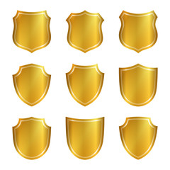 Gold shield shape icons set. 3D golden emblem signs isolated on white background. Symbol of security, power, protection. Badge shape shield graphic design Vector illustration