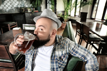 Bearded man drinking beer in pub