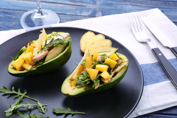 Plate with chicken salad in boats from avocado on table