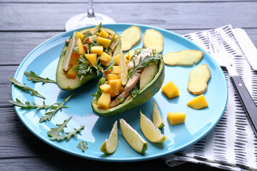 Plate with chicken salad in boats from avocado on table