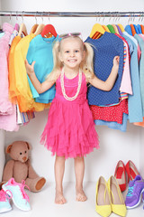 Cute small girl in wardrobe with clothes