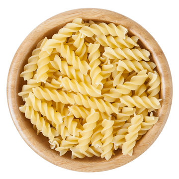 Fusilli pasta in wooden bowl isolated on white background with clipping path