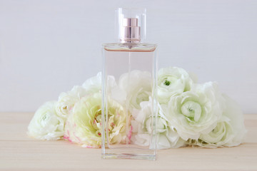 Obraz na płótnie Canvas perfume bottle next to aromatic flowers on white table