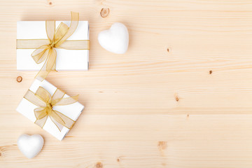 holiday and celebration composition. presents or gifts with gold ribbon and white hearts on wooden background with copy space for text. wedding or anniversary concept. flat lay. top view