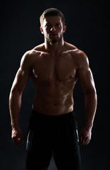 Fototapeta na wymiar Vertical studio shot of a silhouette of a muscular male athlete posing shirtless on black background fitness gym anonymous mysterious incognito sportsman lifestyle confidence concept.
