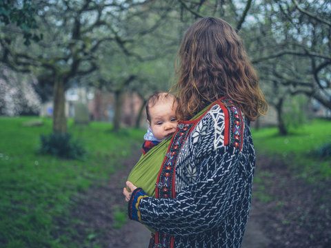 Woman with baby in carrier in the park