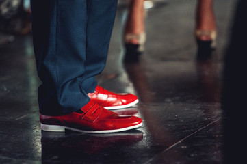Fototapeta na wymiar Men feet in classical pants and trendy red shoes