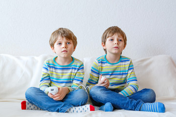 Two little kid boys playing video game at home
