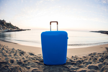 Travel, holiday and vacation concept - blue suitcase on the beach.